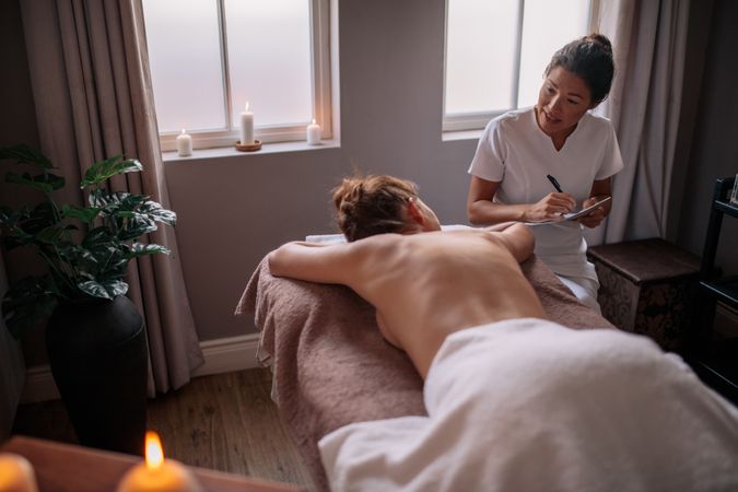 Massage therapist talking to woman and making notes