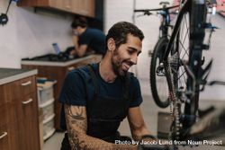 Smiling man working on a bicycle in a repair shop 4AMJQ4