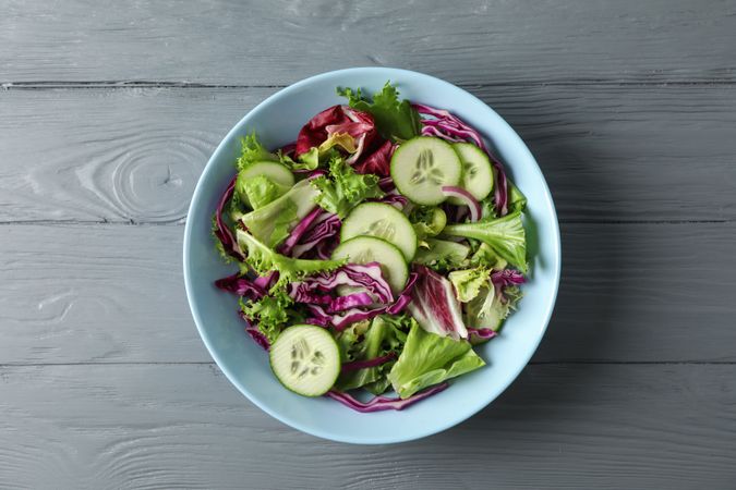 Plate with fresh salad on wooden background, space for text