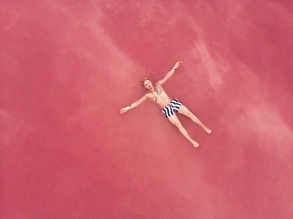 Carefree man on vacation delighting in pink water of lake
