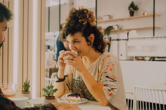 Positive woman drinking coffee in cafe