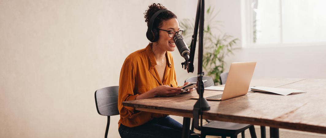 Female working from home recording a podcast on a laptop