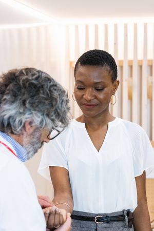 Older male doctor measuring pulse of patient