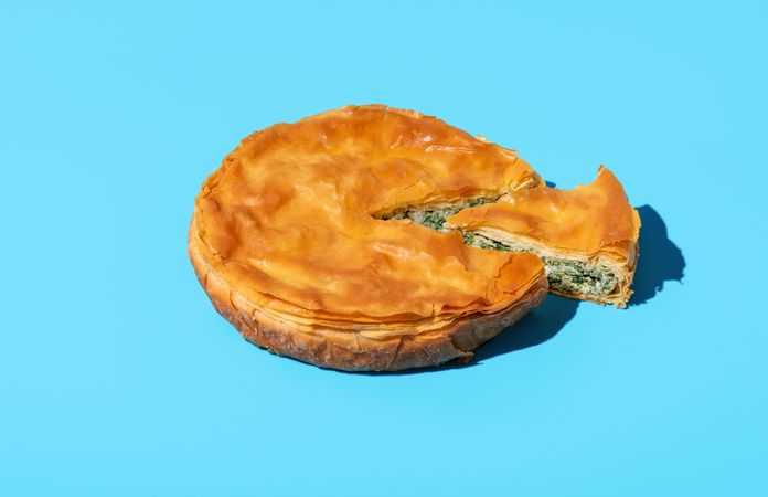 Phyllo spinach pie isolated on a blue background