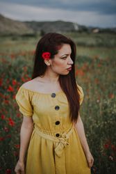 glad adult woman holding rose and looking at camera while standing in meadow