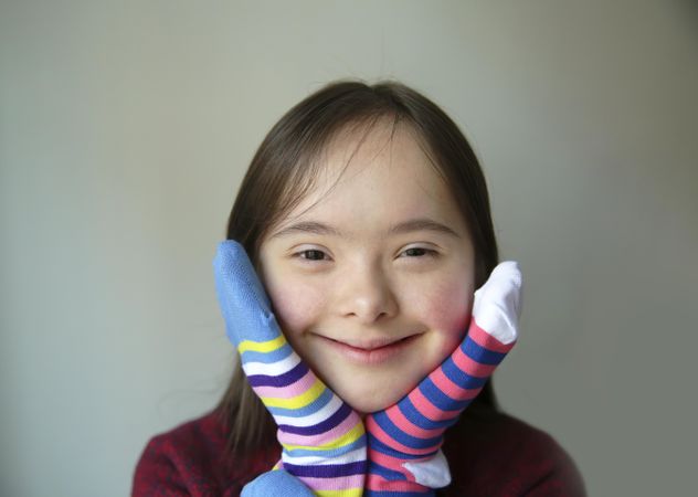 Close up of happy girl smiling with socks on her hands around her face