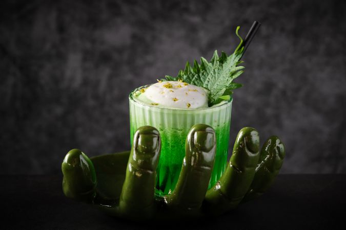 Green cocktail with shiso leaf served on creative plate