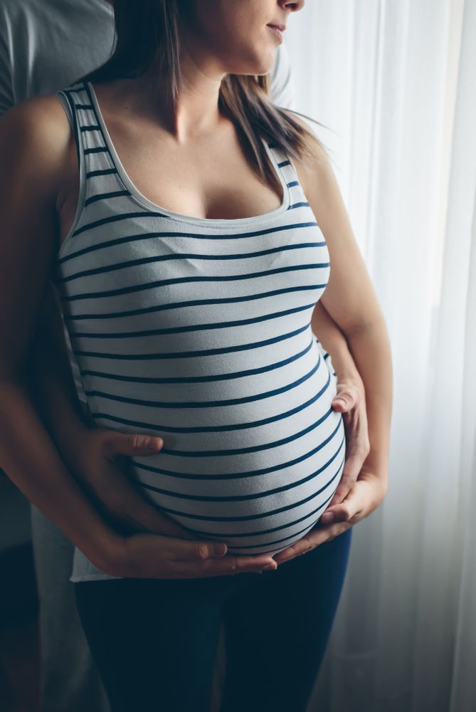 Pregnant woman embraced by her husband