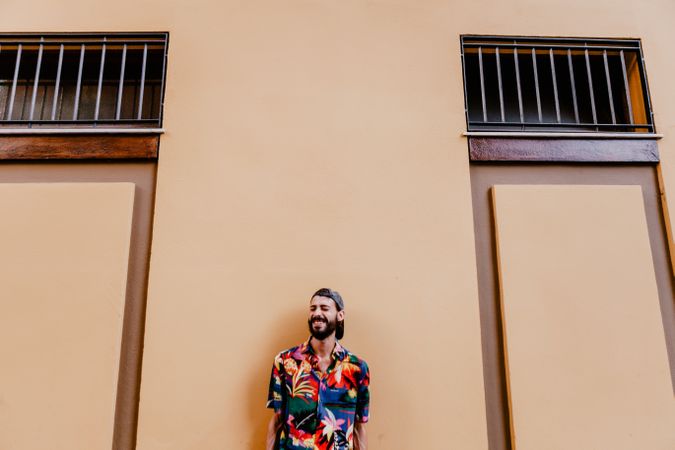 Laughing colorful male against orange wall