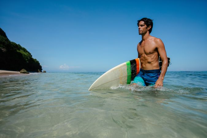 Young man with surf board walking out of the sea