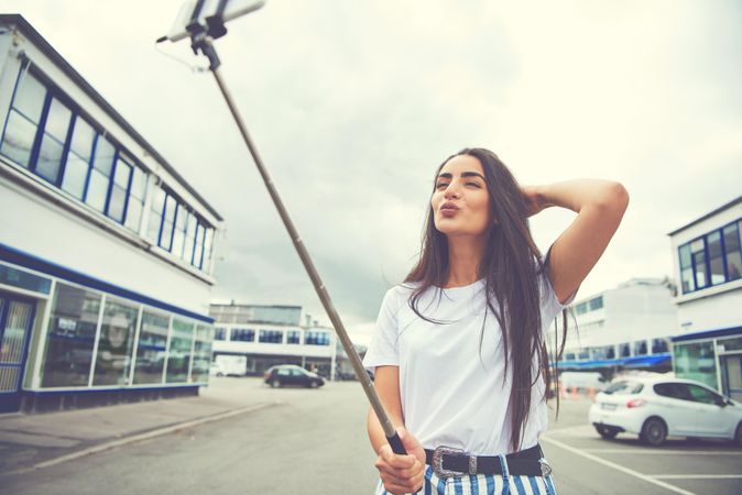 Brunette woman making air kiss at selfie stick