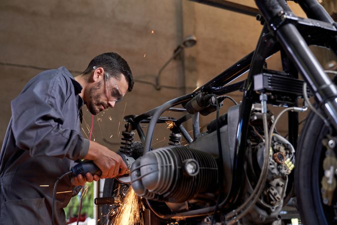 Focused mechanic repairing motorbike using angle grinder