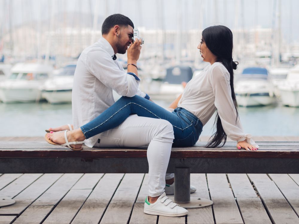 Man taking photo and sitting with man on bench