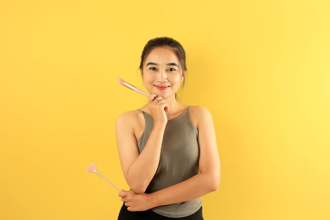 Asian Young Woman Holding Make Up Brush Smiling to the Camera