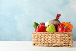 Wicker basket and vegetables on wooden background, copy space