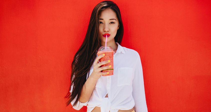 Close up of a woman drinking juice using a straw