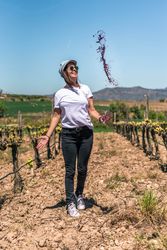 Excited woman spilling red wine from glass in hands