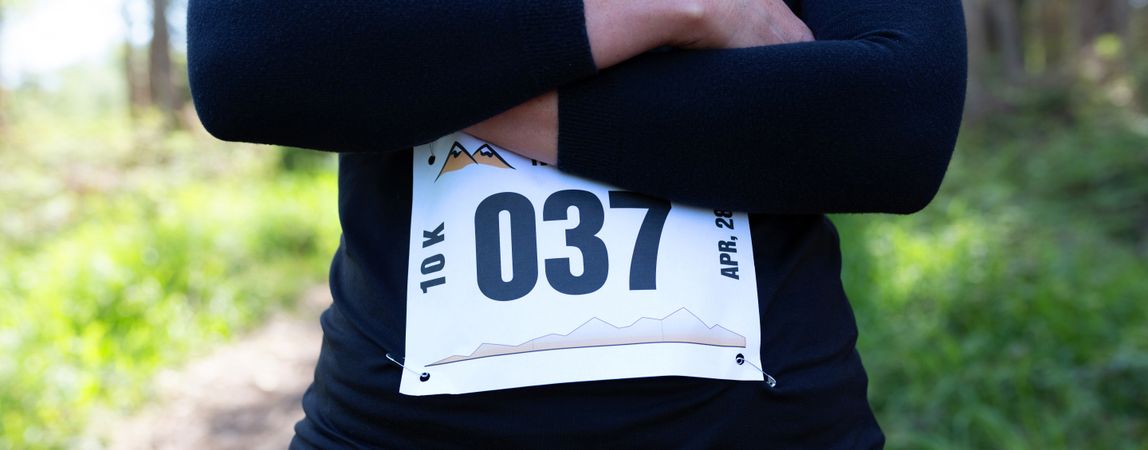 Unrecognizable female trail athlete posing with race number