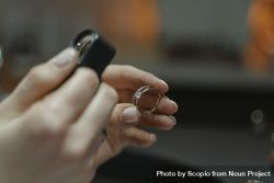 Cropped image of jeweler holding a magnifier to inspect a gold ring 4376O4