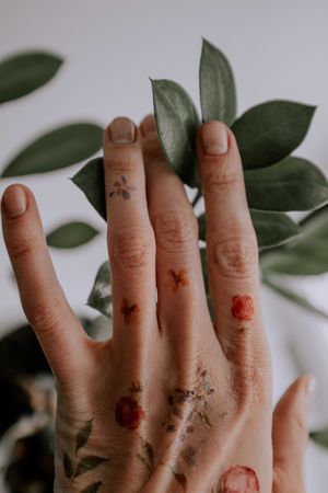 Tattooed hand beside green plant