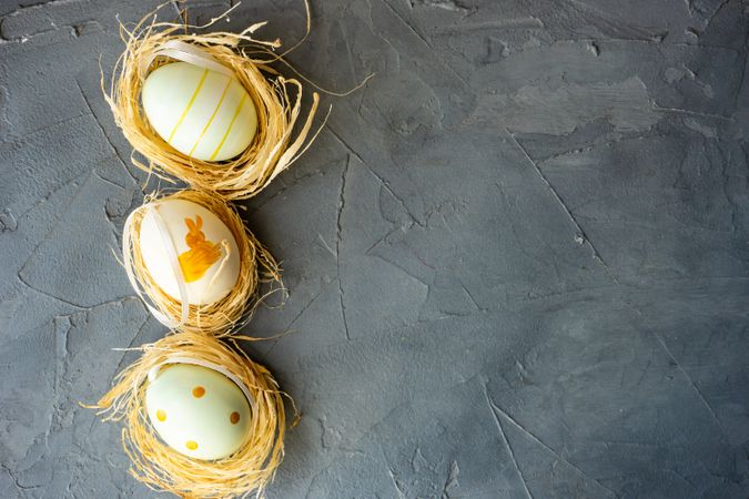 Top view of three pastel decorative eggs in nests
