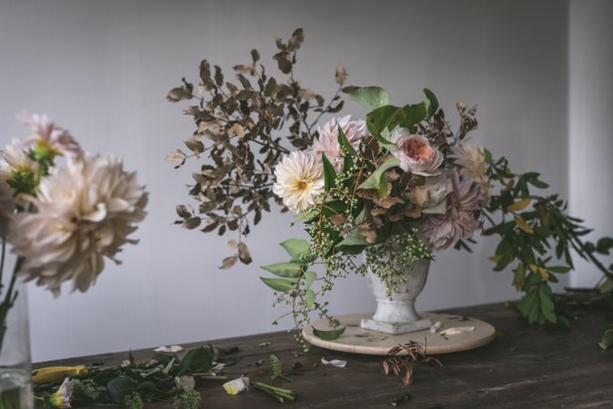 Composition of flowers and plants in vintage vase on board