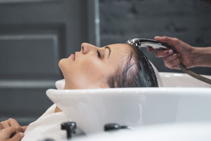 Side view of stylist washing hair