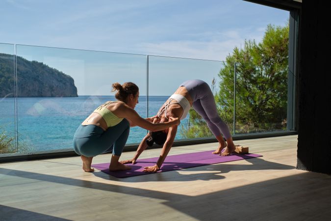 Fit woman doing Downward Facing Dog with personal instructor