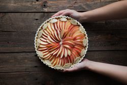 unrecognizable woman showing a tasty apple pie on a wooden table