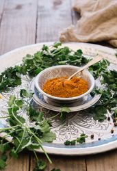 Turmeric in silver bowl with herbs on table