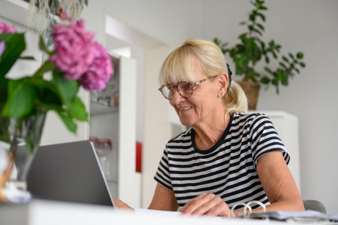 Happy mature woman using laptop in living room at home