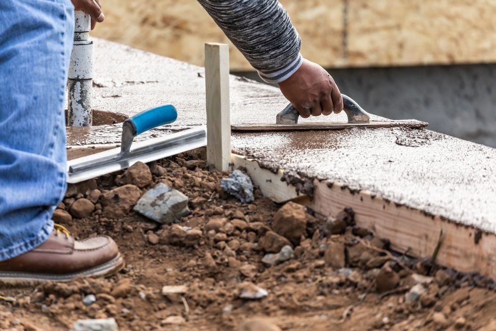 Construction Worker Using Wood Trowel On Wet Cement Forming Coping Around New Pool
