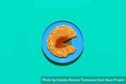 Top view of pancake topped with maple syrup on bright blue plate and green background 5qm6K5