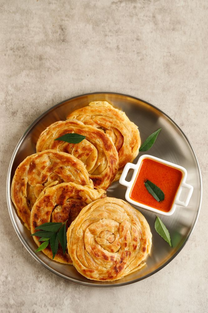 Round plate of roti parata or roti canai with dipping sauce
