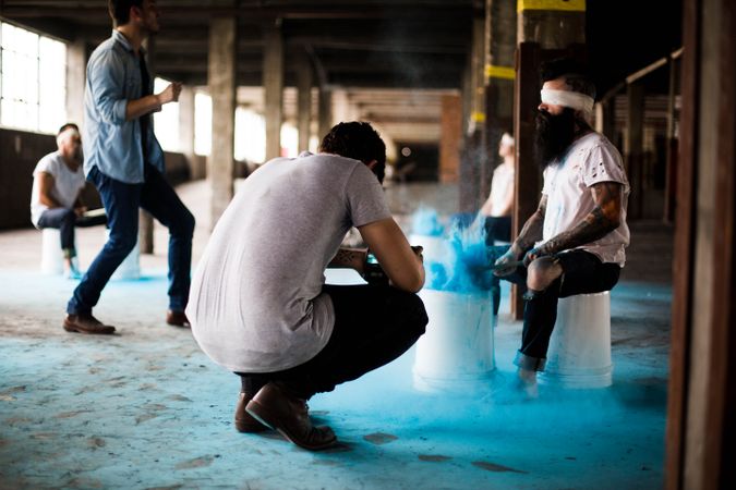 Photographer taking photo of blindfolded man playing drums with blue powder