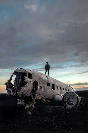 Man standing on wrecked airplane in the middle of nowhere