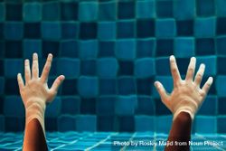 Two hands reaching out under water in a pool 0Vdwk4