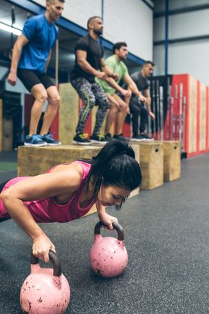 Sportswoman doing push-ups with kettlebells
