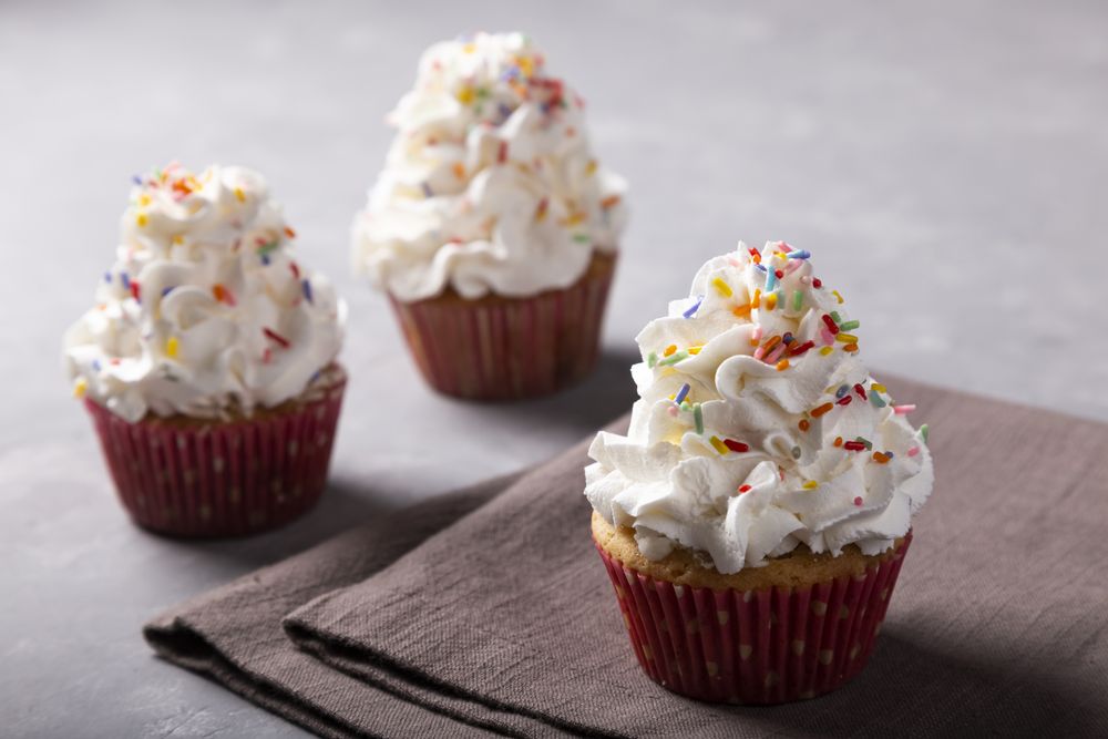 Tasty party cupcakes on the table. Cupcakes with whipped cream.