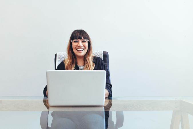 Smiling creative artist sitting at her desk in office working on a laptop
