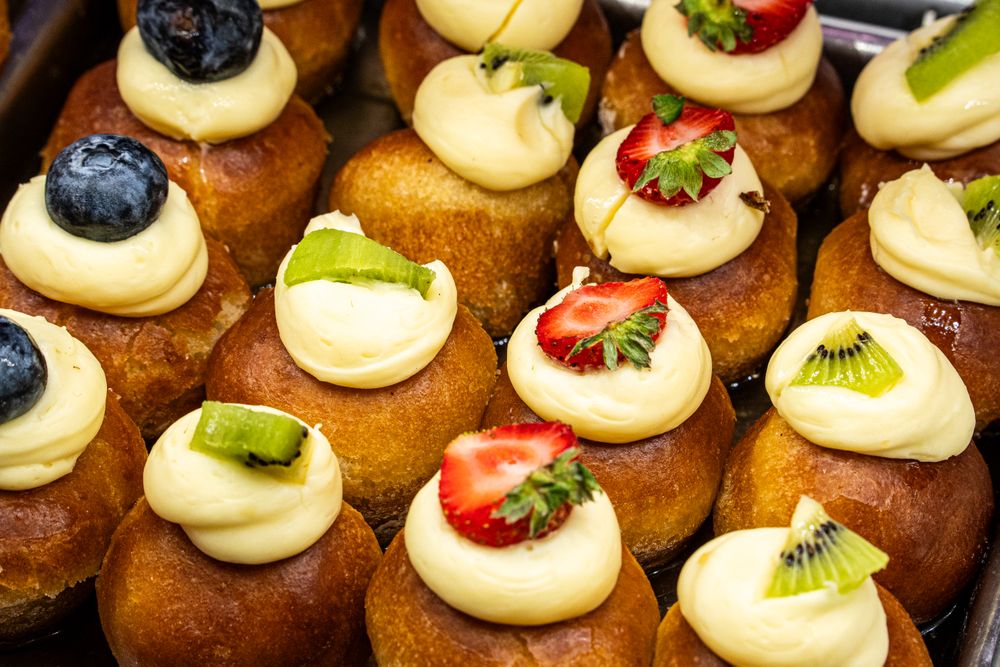 Colorful cream puffs decorated fresh fruits kiwi strawberry blueberry pastry bakery display