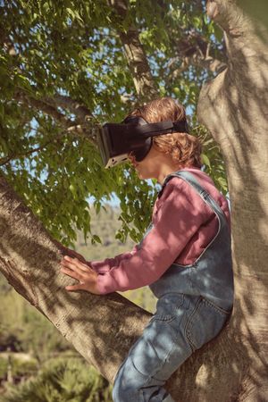 Boy in VR headset sitting on tree