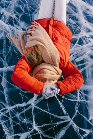 Happy woman in skates lying on ice