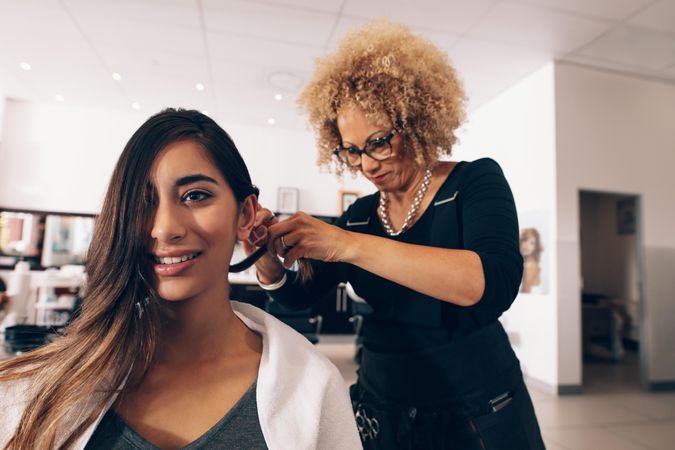 Focused salon owner working on young client’s long hair