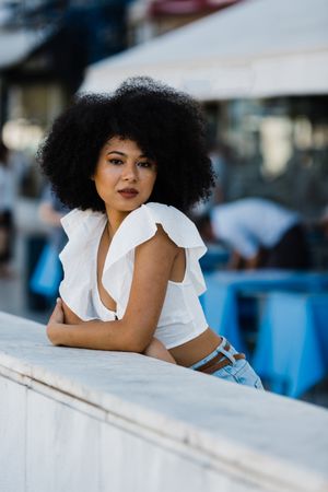 Black female leaning in concrete parapet