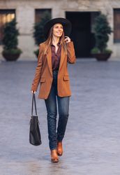 Gorgeous woman in fashionable outfit strolling on city street