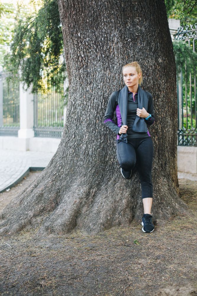 Woman resting on tree trunk after jogging