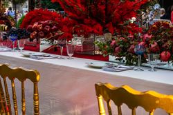 Formal dinner table with red seats and red floral arrangements