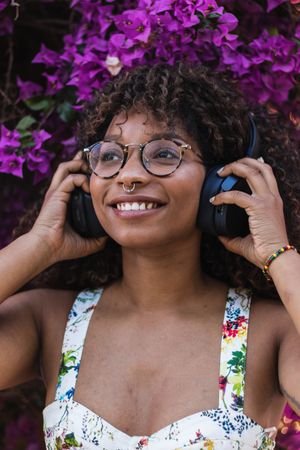 Black woman listening to music near flowers