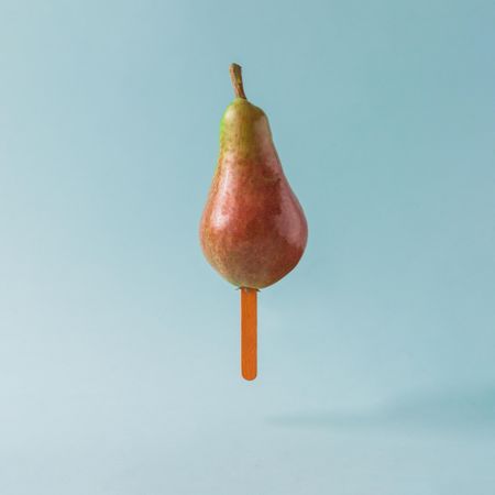 Pear with ice cream stick on pastel blue background